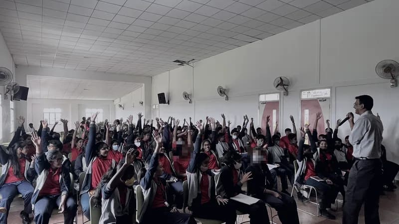School students with their hands raised during a FLY workshop