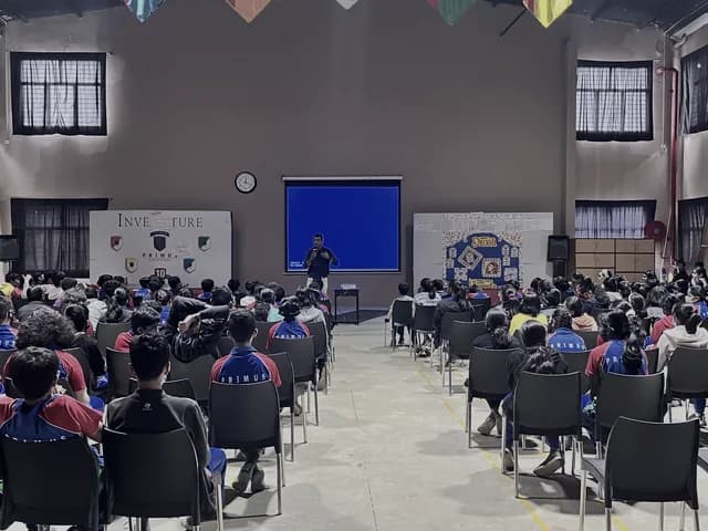 Students seated in a school hall facing a presentation
