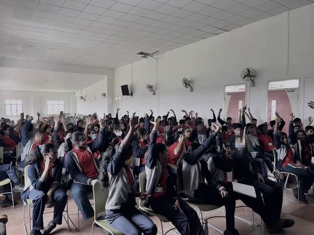 School students with their hands raised during a workshop